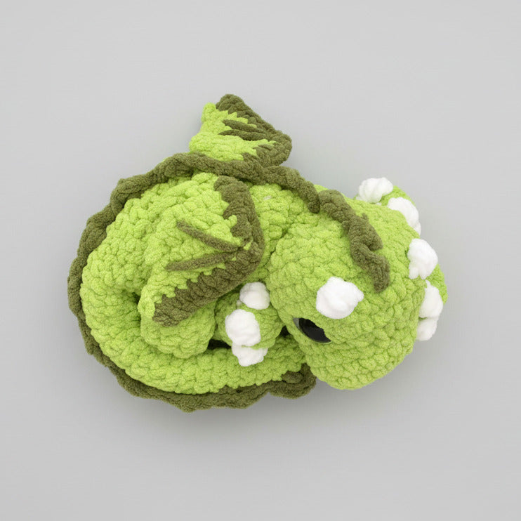 Handmade crocheted sleepy dragon plush made with soft plush blanket yarn and large safety eyes, approximately 14" wide and 4" high, perfect for cuddling or fantasy decor.